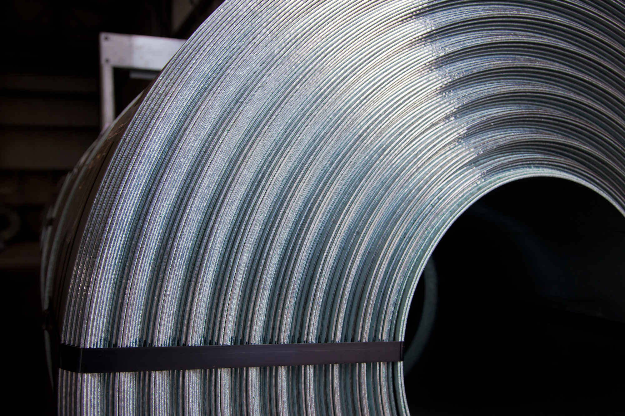 Galvanized steel coils stacked in a climate-controlled metal processing warehouse.